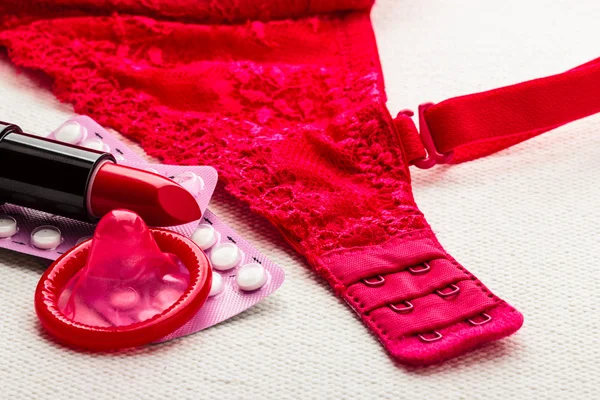 Pills, lipstick and condom with lace lingerie. — Stock Photo, Image