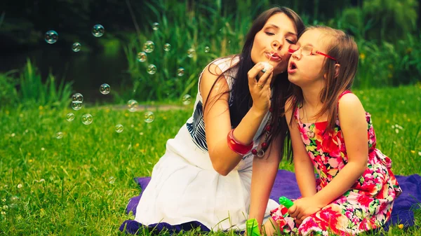 Mother and child blowing soap bubbles outdoor. — Stock Photo, Image