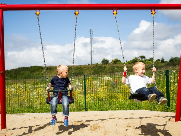 Barn pojkar spelar på svingen utomhus. — Stockfoto