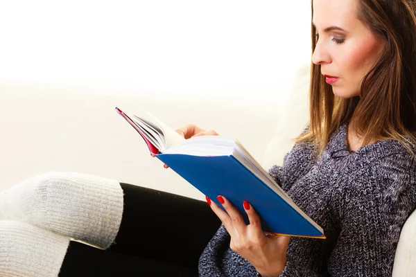 Mujer sentada en el sofá leyendo libro en casa — Foto de Stock