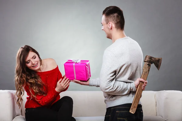 Insincire man holding axe giving gift box to woman — Stock Photo, Image