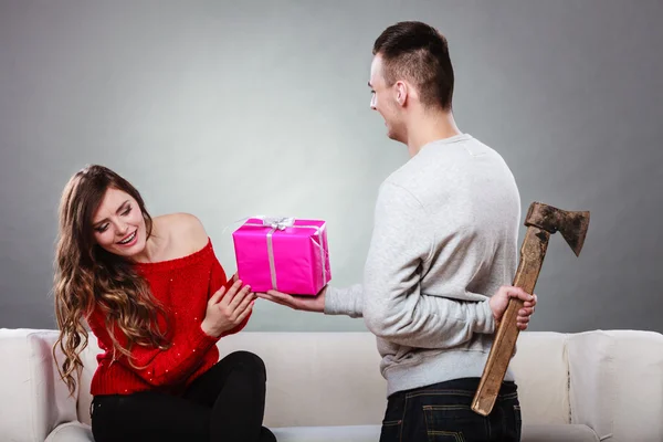 Insincire hombre sosteniendo hacha dando caja de regalo a la mujer — Foto de Stock