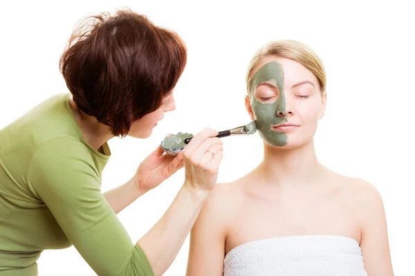 Cosmetician tillämpar lera ansiktsmask på kvinna ansikte. — Stockfoto