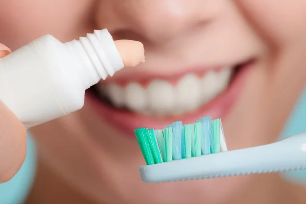 Woman putting toothpaste on toothbrush — Stock Photo, Image
