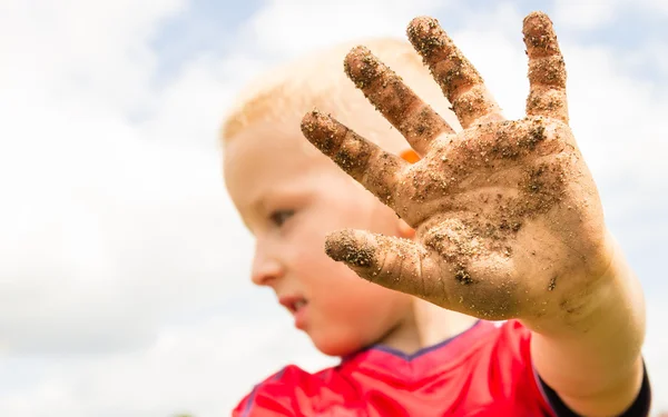 Child playing outdoor showing dirty muddy hands. — Stock Photo, Image