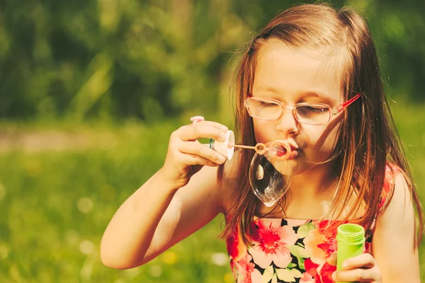 Liten flicka barn blåsa bubblor utomhus. — Stockfoto