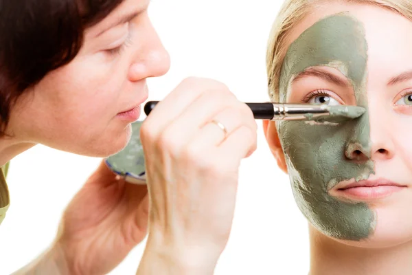 Cosmético aplicando mascarilla facial de arcilla a cara de mujer . — Foto de Stock