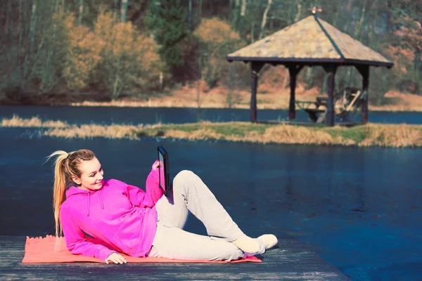 Girl lying in park using tablet. — Stock Photo, Image