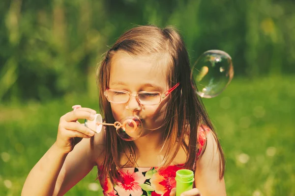 Petite fille enfant soufflant des bulles en plein air . — Photo