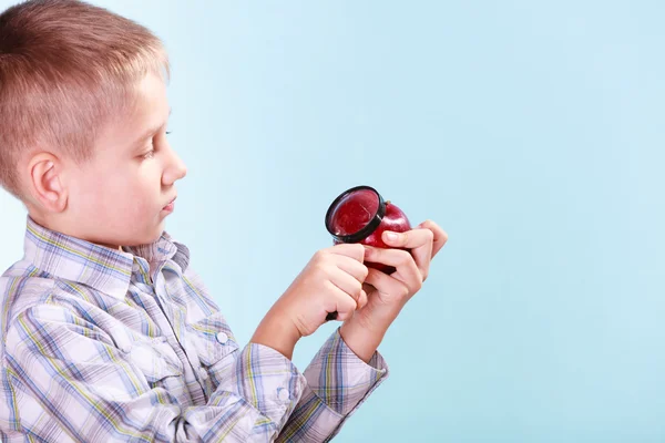 Kid undersöka apple med förstoringsglas. — Stockfoto