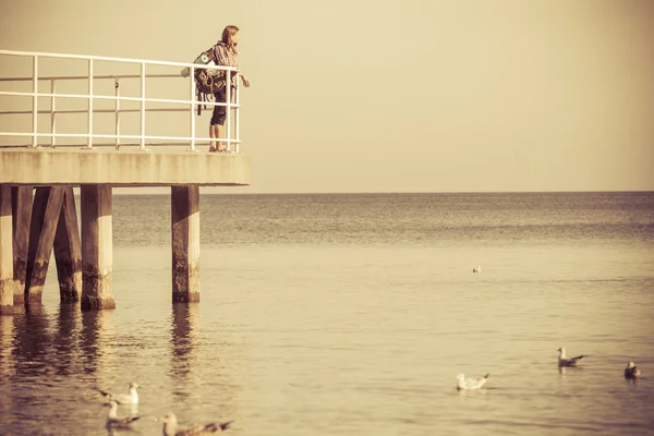 Man wandelaar met rugzak op pier, landschap van zee — Stockfoto