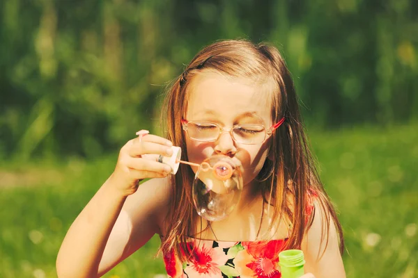 Lilla flickan barnet blåser såpbubblor utomhus. — Stockfoto