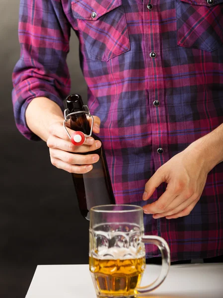 Ung man häller öl från flaska i mugg — Stockfoto