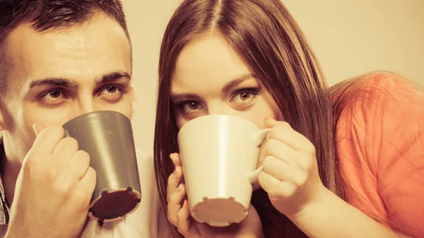 Young couple holds mugs with tea or coffee — Stock Photo, Image