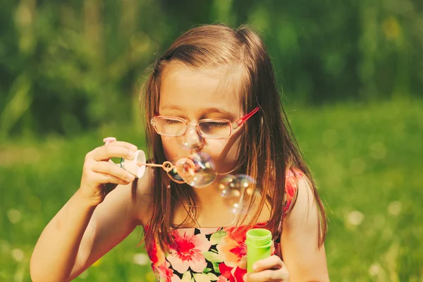 Liten flicka barn blåsa bubblor utomhus. — Stockfoto