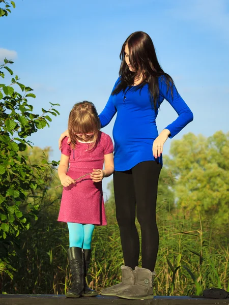 Kobieta w ciąży z córką w parku odkryty — Zdjęcie stockowe