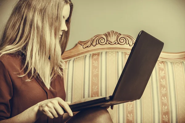 Fashion woman sitting on sofa using pc laptop — Stock Photo, Image