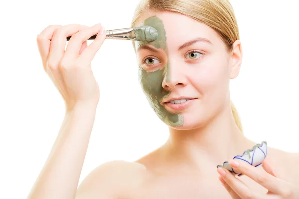 Menina aplicando máscara de barro facial em seu rosto — Fotografia de Stock