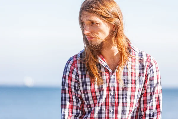 Homem longo cabelo relaxante à beira-mar — Fotografia de Stock