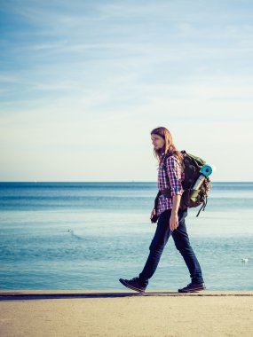 Man hiker with backpack tramping by seaside clipart
