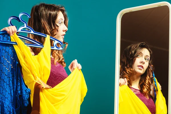 Vrouw shopper houdt hangers met kleding kijken in spiegel — Stockfoto