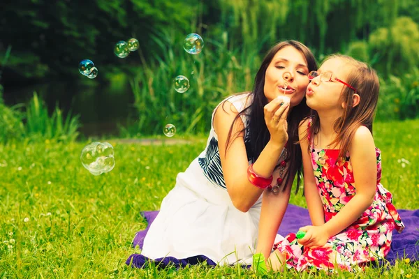 Mother and child blowing soap bubbles outdoor. — Stock Photo, Image