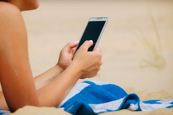 Mujer en la playa mensajes de texto en el teléfono inteligente . — Foto de Stock