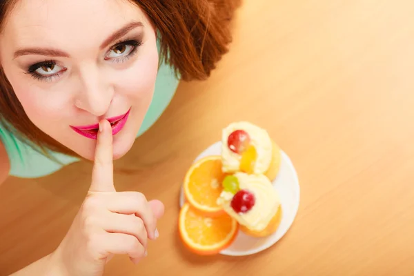 Woman eating cake showing quiet sign. Gluttony. — Stock Photo, Image