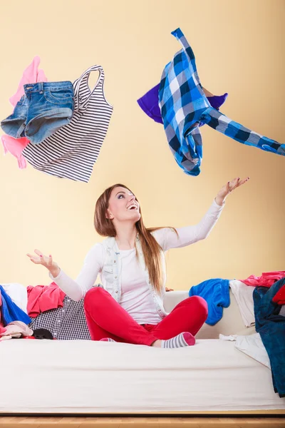 Happy woman on sofa in messy room throwing clothes — Stock Photo, Image