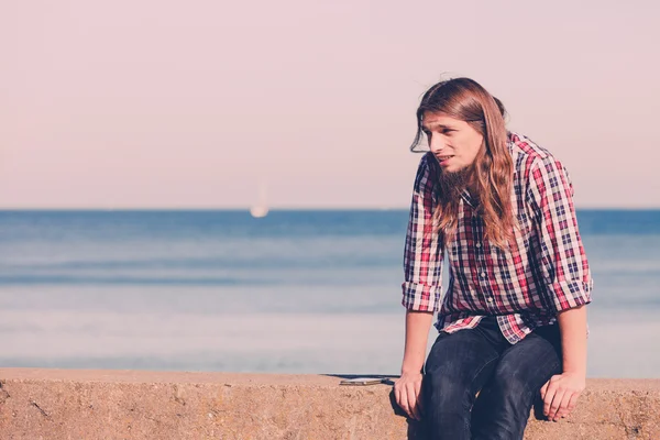 Man lang haar ontspannen door de zee — Stockfoto