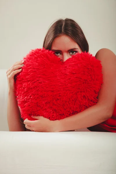 Mulher abraçando travesseiro forma coração vermelho — Fotografia de Stock