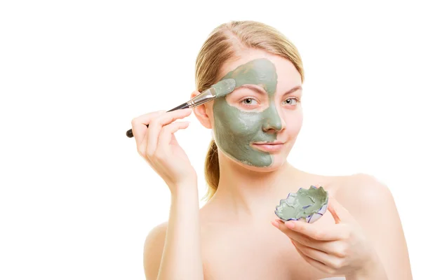 Chica aplicando mascarilla de arcilla facial en su cara — Foto de Stock