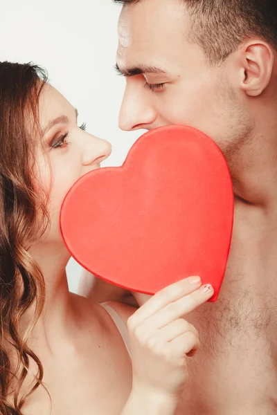 Älskande par kyssas bakom rött hjärta. Kärlek. — Stockfoto