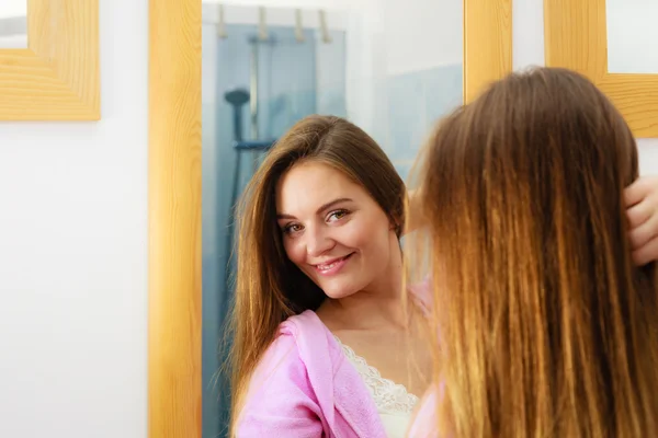 Kvinnan tar hand om hennes långa hår i badrum — Stockfoto