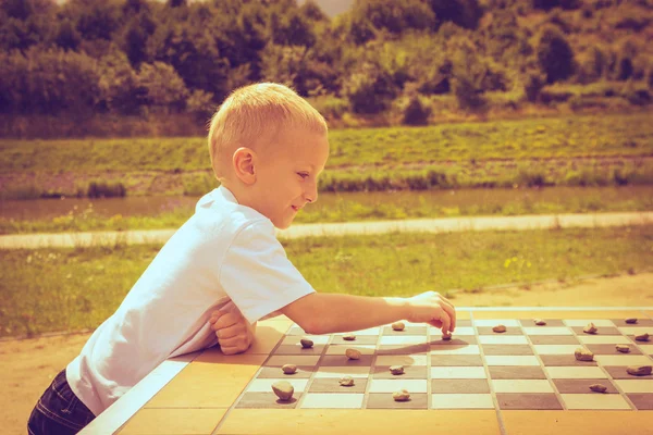 Little boy clever child playing checkers in park — Stock Photo, Image