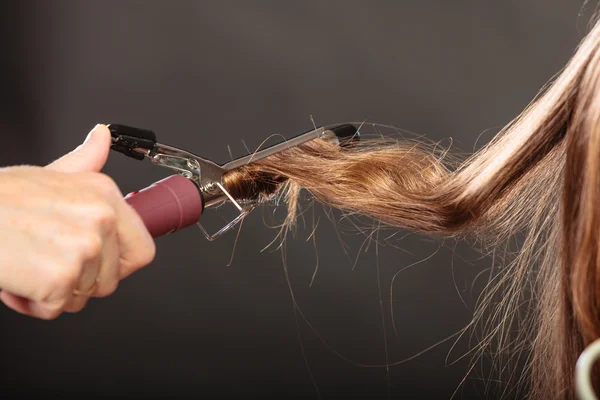 Stylist curling hair for young woman. — Stock Photo, Image