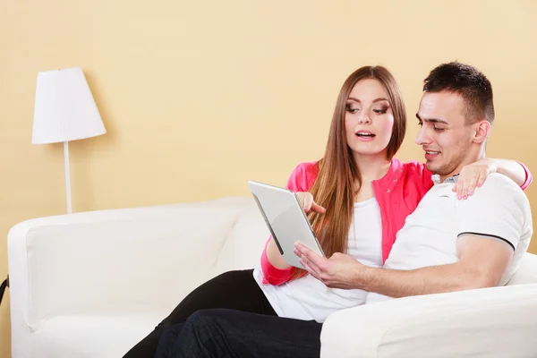 Couple with tablet sitting on couch at home — Stock Photo, Image