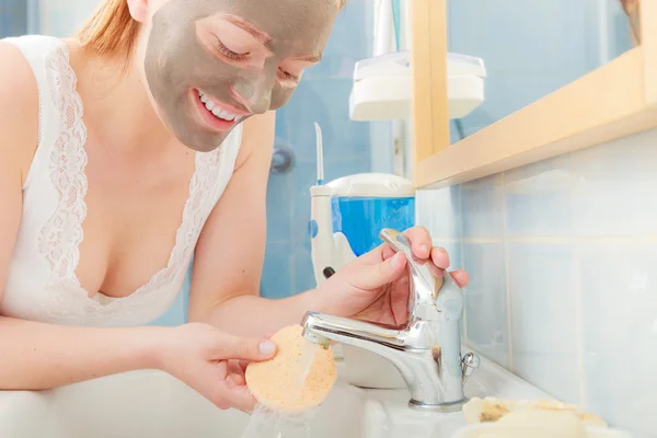 Woman removing mask in bathroom — Stock Photo, Image