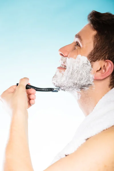 Jeune homme rasage à l'aide d'un rasoir avec mousse crème . — Photo