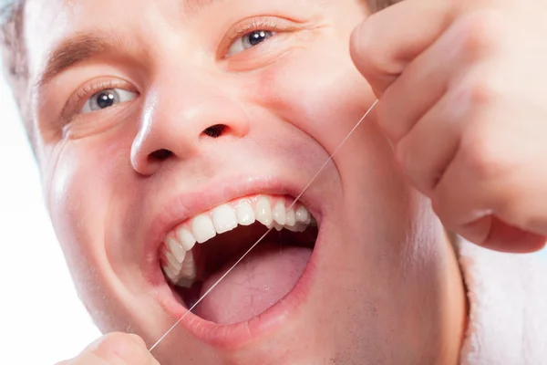 Jovem limpando seus dentes brancos com fio dental — Fotografia de Stock