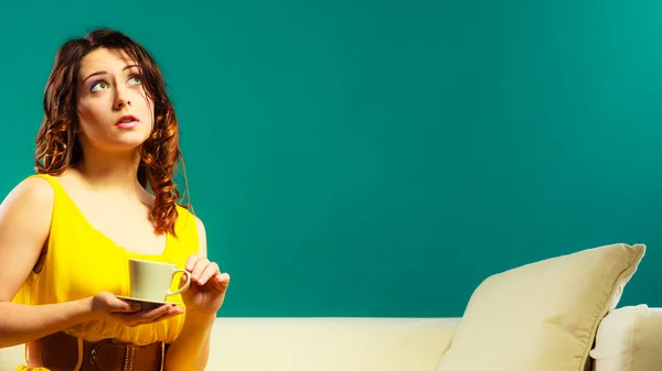 Vrouw zittend op de bank houdt koffiekop — Stockfoto