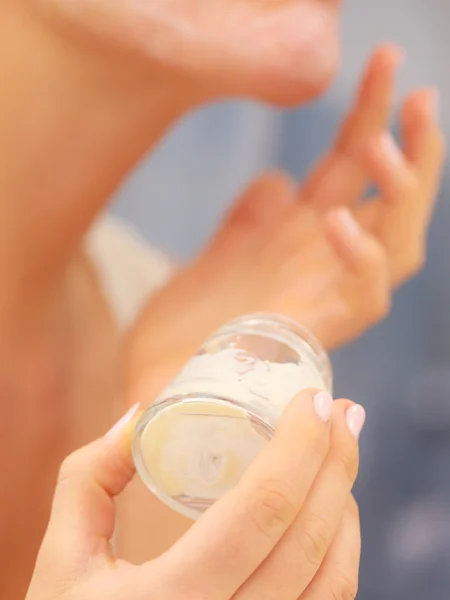 Mujer aplicando crema mascarilla en la cara en el baño —  Fotos de Stock