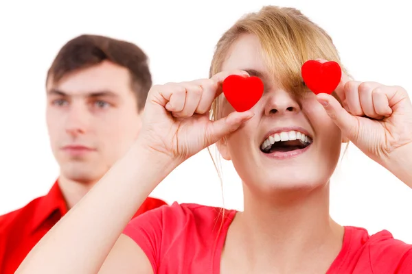 Vážný muž a bláznivá žena drží červené srdce přes oči — Stock fotografie