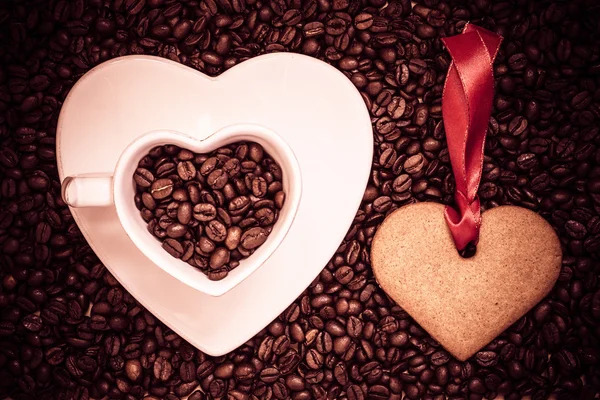 Copa en forma de corazón y galletas en el fondo de granos de café —  Fotos de Stock