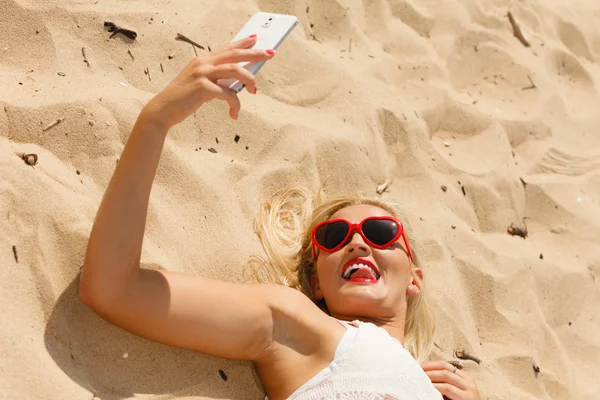 Woman lying on sandy beach using cell phone — Stock Photo, Image