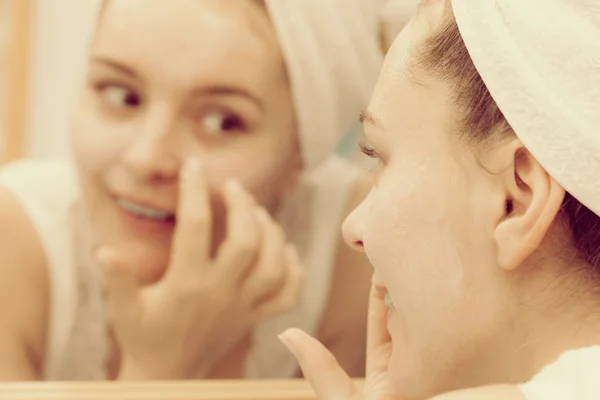 Woman applying mask cream on face in bathroom — Stock Photo, Image