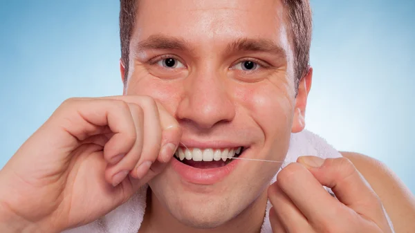 Young man cleaning her white teeth with dental floss