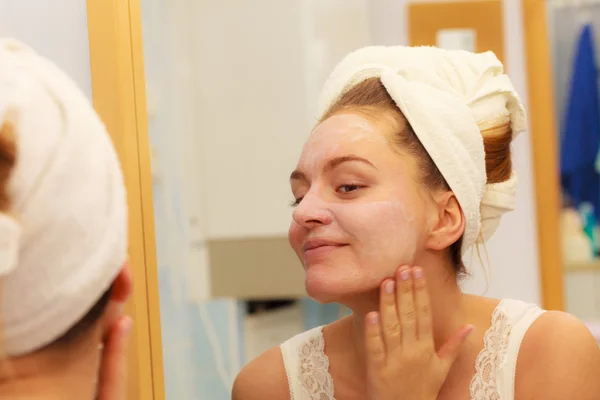 Mujer aplicando crema mascarilla en la cara en el baño —  Fotos de Stock