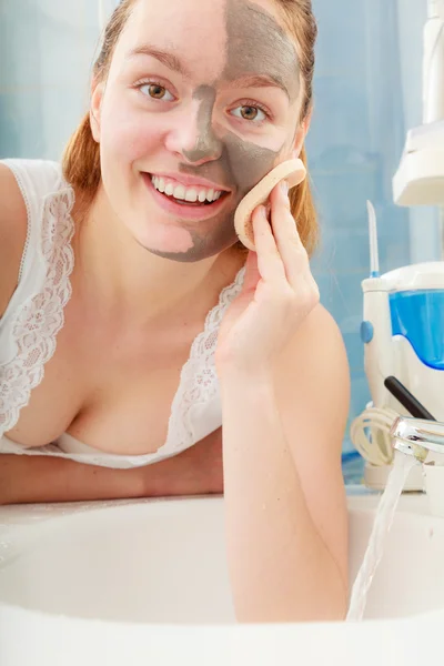 Mulher removendo máscara de barro facial lama no banheiro — Fotografia de Stock