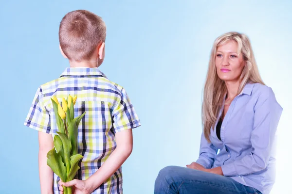 Niño pequeño con madre sostener flores detrás de la espalda . —  Fotos de Stock